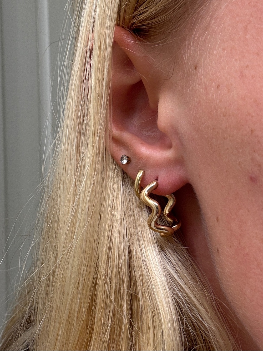Gold hoop earrings with a wavy, twisted design